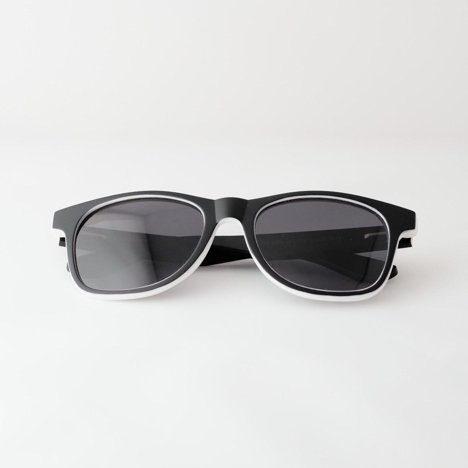 Bamboo sunglasses , folded . Dark grey lenses, polarized, and matte black and white frame. Designed in Canada