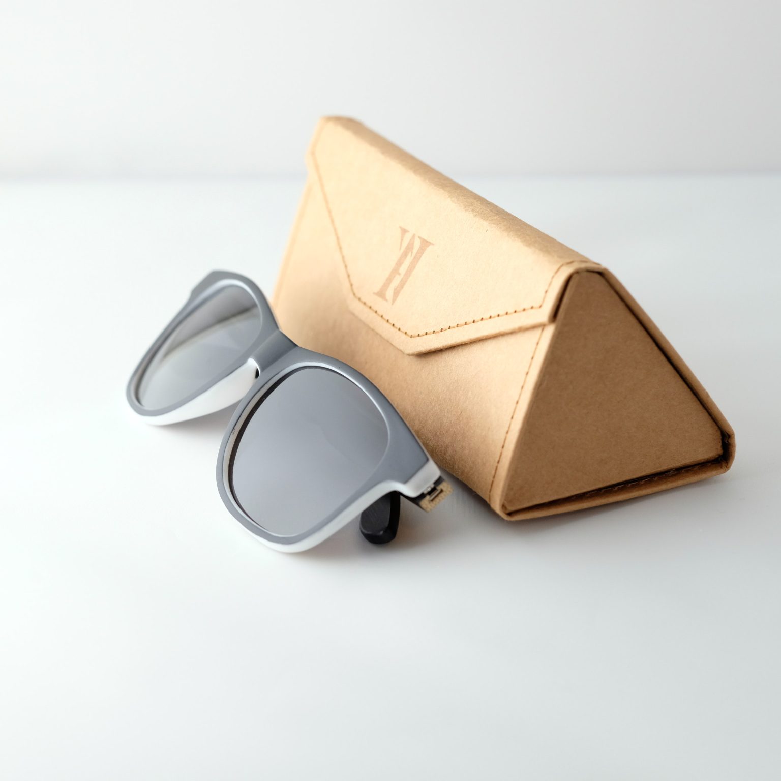 Bamboo sunglasses , next to case . Dark grey lenses, polarized, and matte black and white frame. Designed in Canada