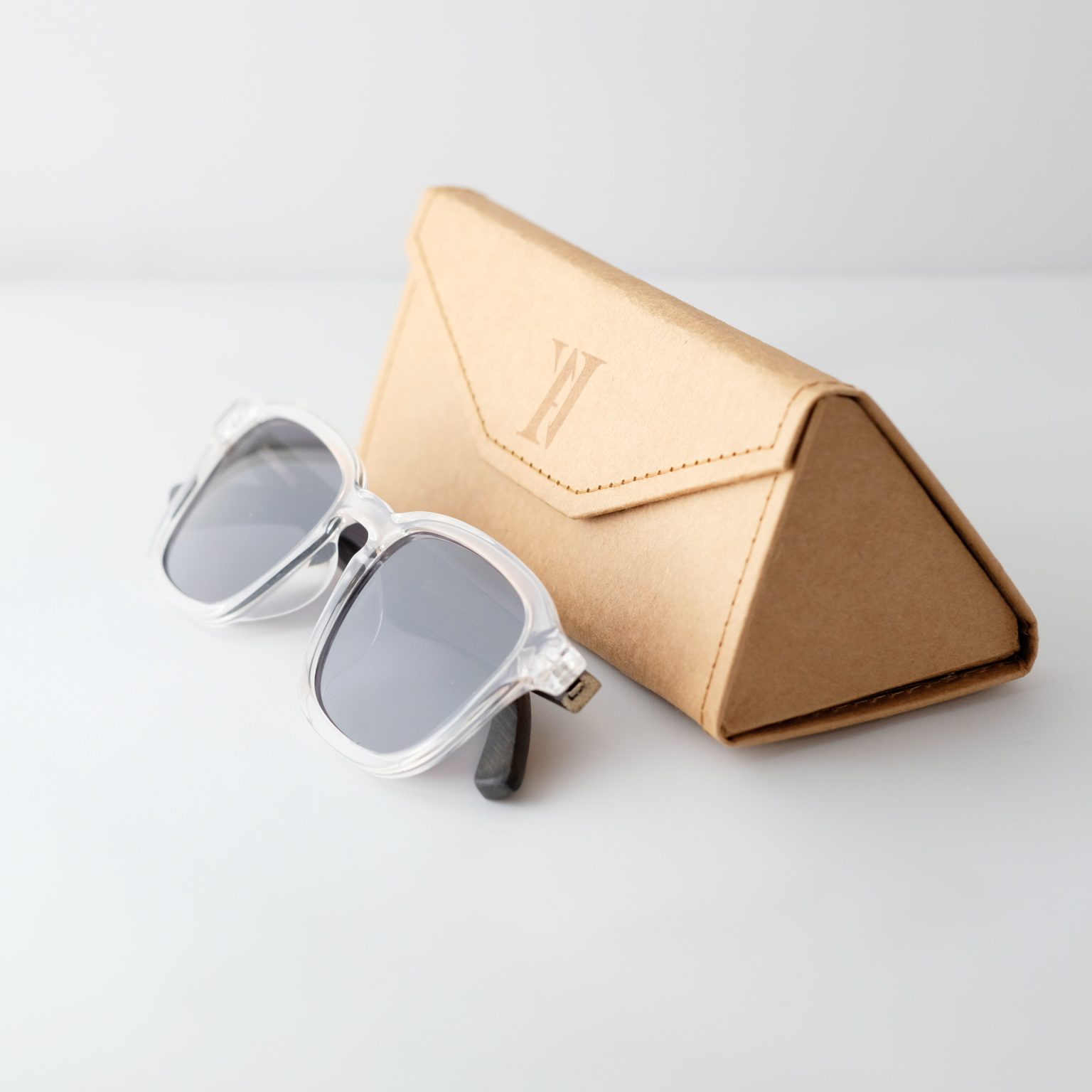 Bamboo sunglasses folded on white background, white frames, grey lenses and black arms.