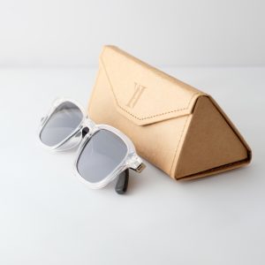 Bamboo sunglasses folded on white background, white frames, grey lenses and black arms.