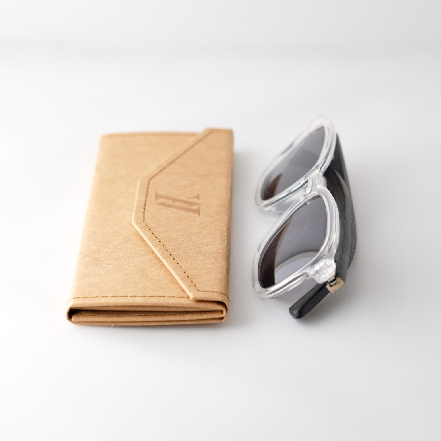 Bamboo sunglasses folded on white background, white frames, grey lenses and black arms.