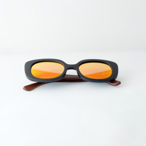Bucharest Sunset bamboo sunglasses folded on a white background. They have orange reflective lenses, black frame and brown arms
