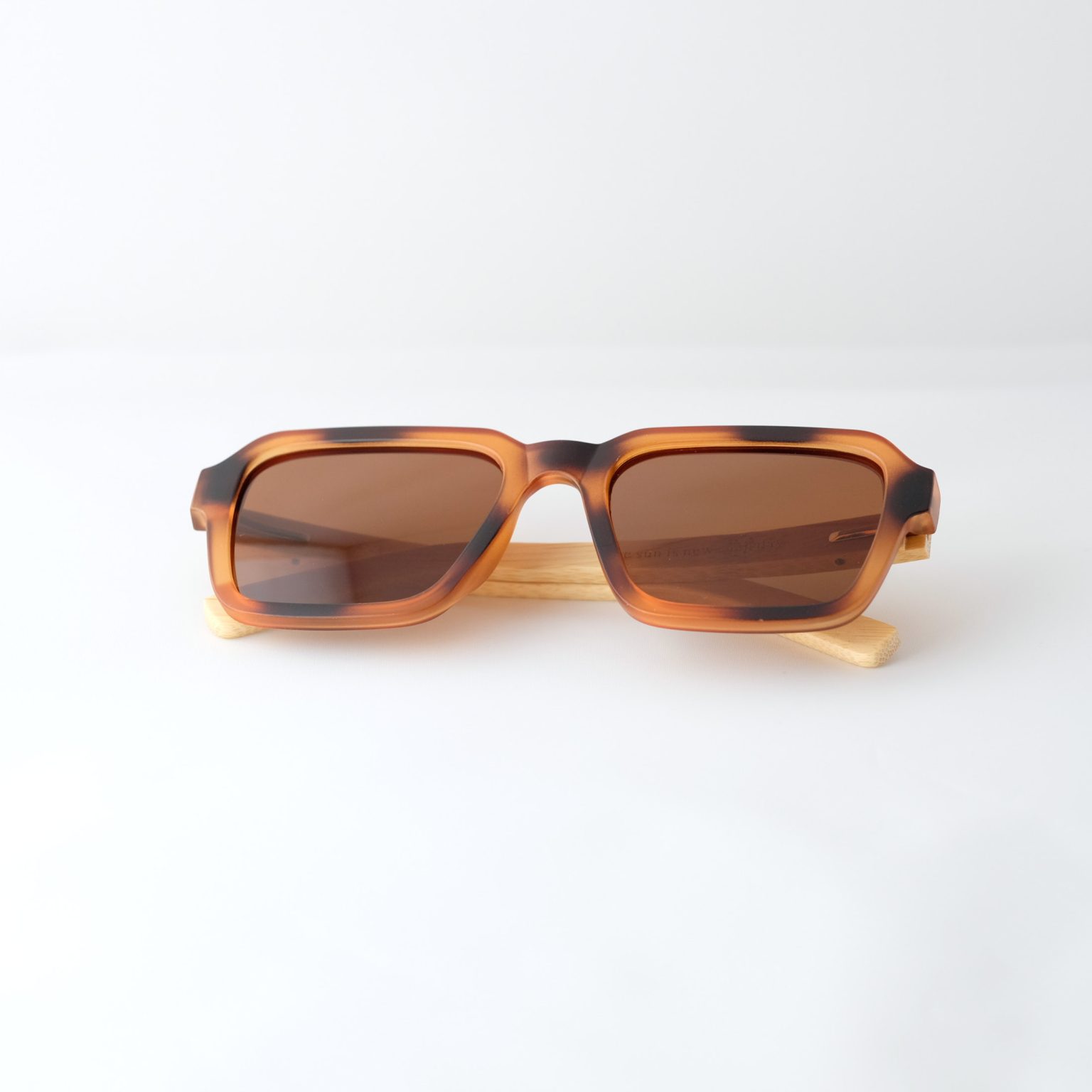Carpathia bamboo sunglasses folded on a white background, with tortie frame, brown lenses and light brown natural bamboo arms.