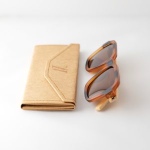 Carpathia bamboo sunglasses folded next to a folded case on a white background, with tortie frame, brown lenses and light brown natural bamboo arms.