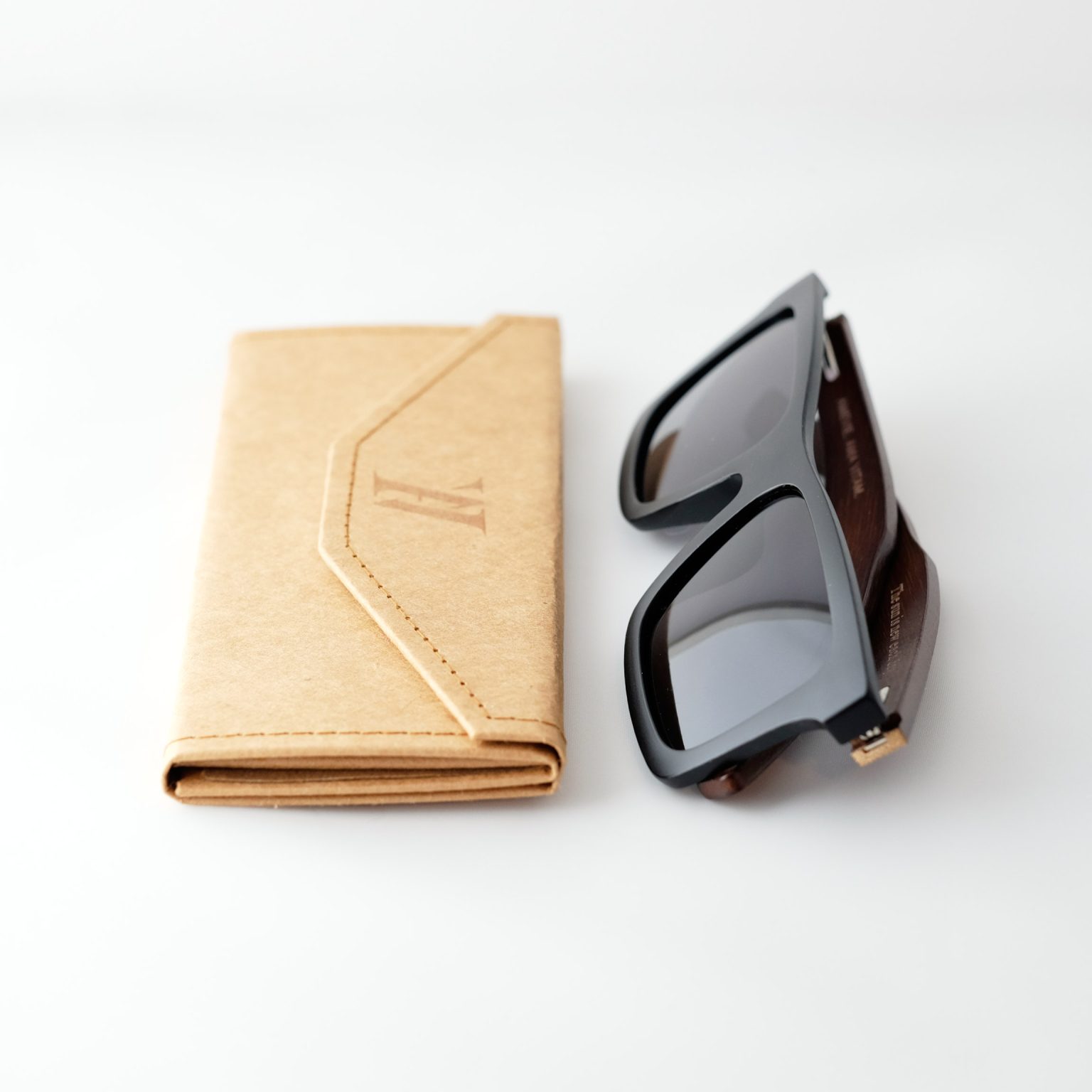 bamboo sunglasses on white background, folded next to case; with brown arms and matte black frames. Smokey dark grey lenses. Designed in Canada
