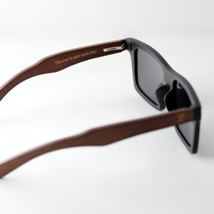 bamboo sunglasses on white background, with brown arms and matte black frames. Smokey dark grey lenses. Inside arm reads 