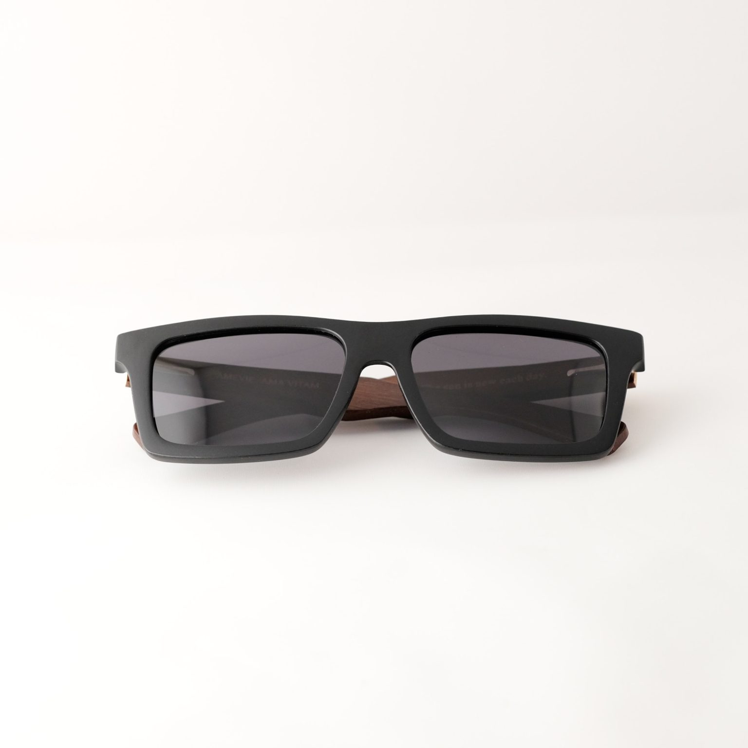 bamboo sunglasses folded on white background, with brown arms and matte black frames. Smokey dark grey lenses. Designed in Canada
