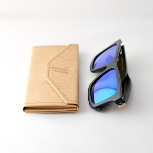 bamboo sunglasses on white background, folded next to folded case. with black arms and matte black frames. blue reflective lenses. Designed in Canada