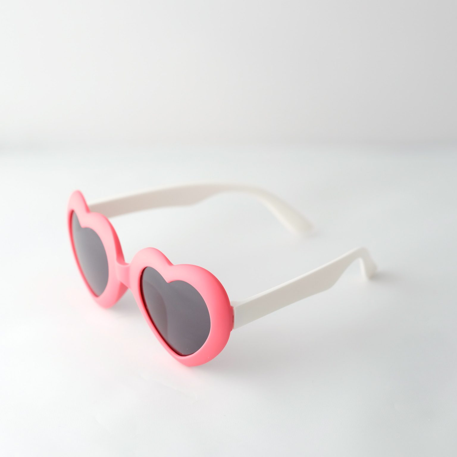 kids sunglasses frame is heart shaped and red, arms are white